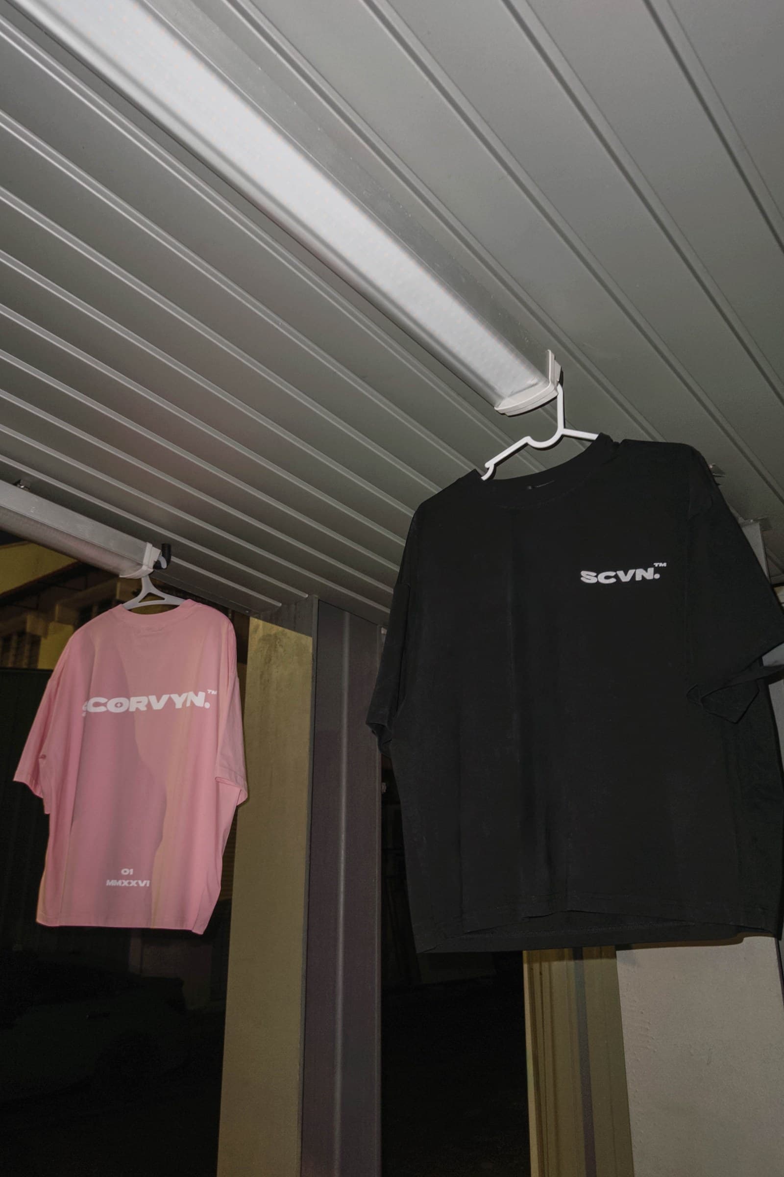 Both colourways hung under a strip light, ink in front, powder behind